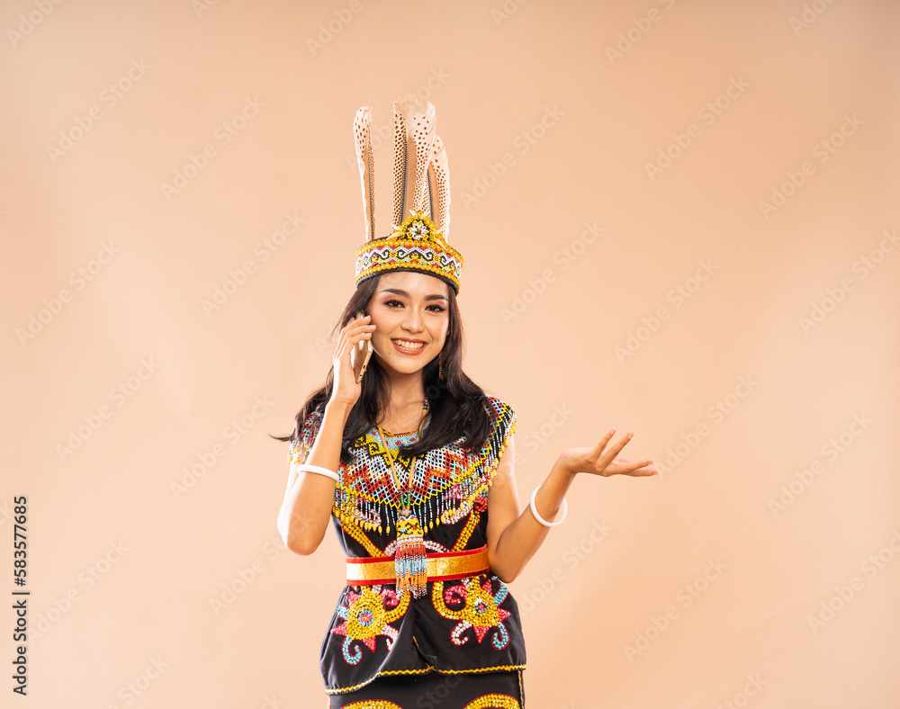asian woman in traditional clothes of dayak tribe smiling while calling using the phone on isolated background