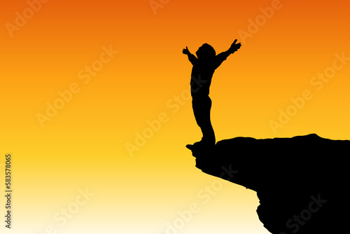 Silhouette of happy man standing raise hand on mountain cliff. Success and serenity concept, young man standing on a rock in the mountains at sunset.