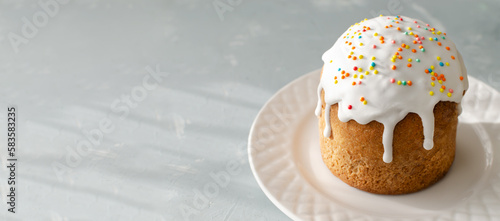Traditional Ukrainian kulich on a white plate on a gray background. The concept of festive Easter baking. Selective focus. Horizontal orientation. Banner. Copy space.