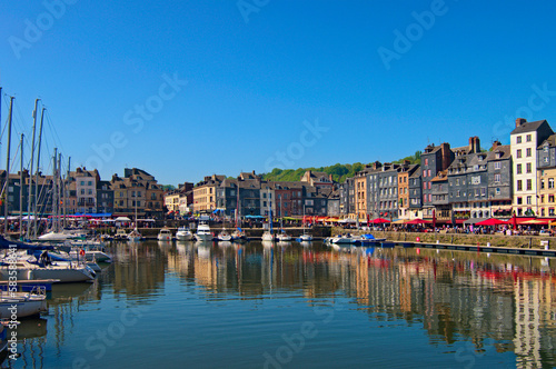 Picturesque landscape view of vintage harbour at the ancient Normandy village Honfleur. Boats  yachts are moored along the embankment with open-air cafes. Travel and tourism concept