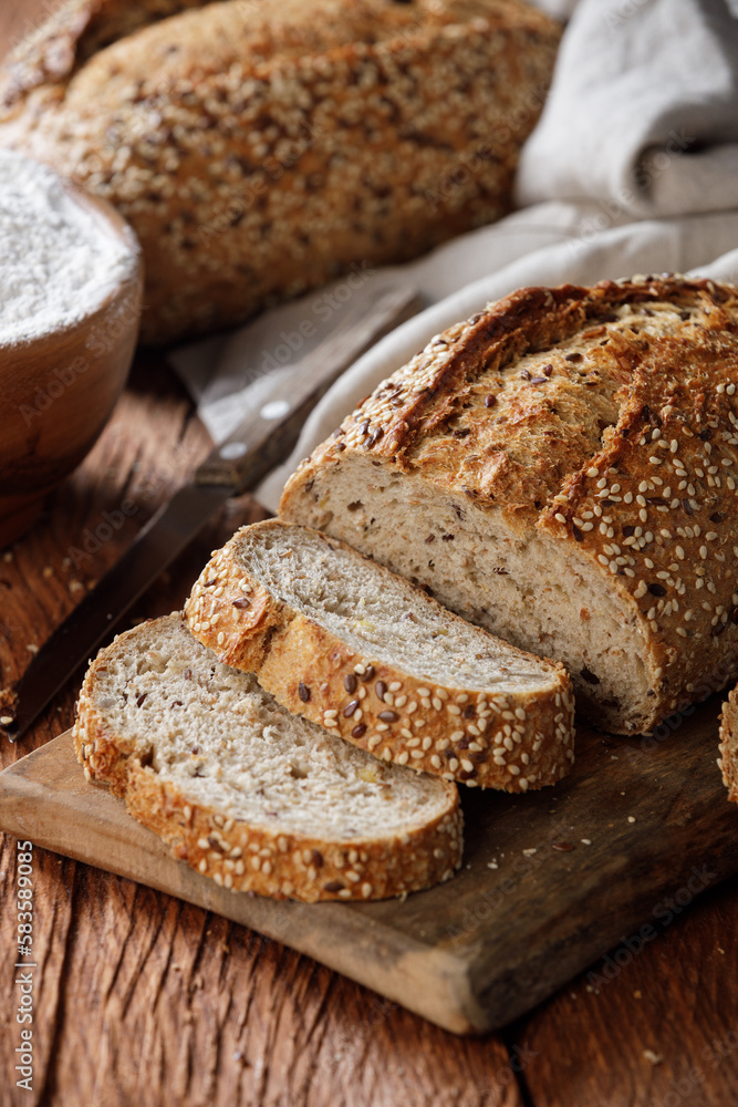 Rustic whole grain bread on a cutting board on a wooden kitchen table