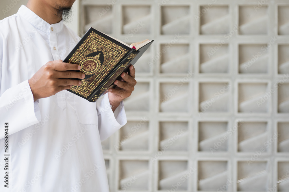 Muslim man reading holy Quran. Holy Quran in Hand with arabic text meaning of Al Quran. Islamic concept background Muslim man reading holy Quran. Holy Quran in Hand with arabic text meaning of Al Quran. Islamic concept background
