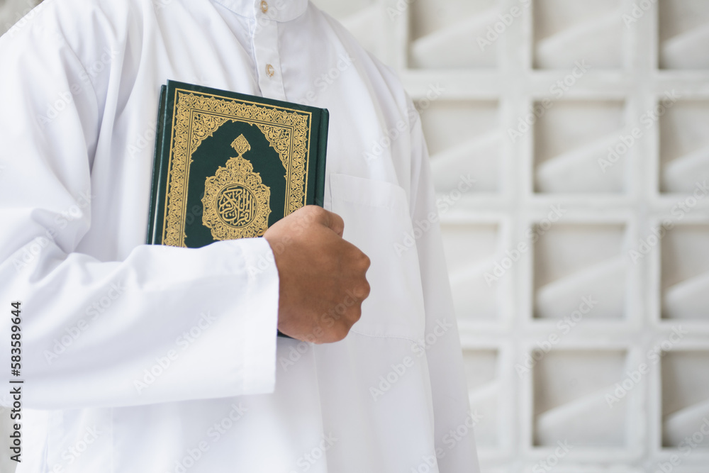 Holy Quran in Hand with arabic calligraphy meaning of Al Quran. Muslim