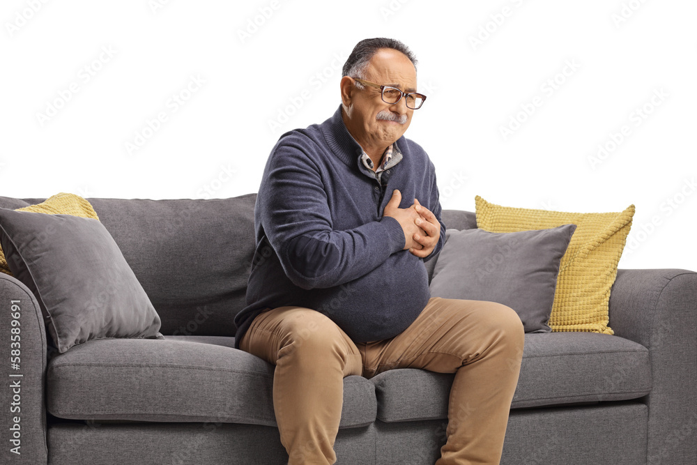 Mature man sitting on a sofa and having a heart attack symptoms