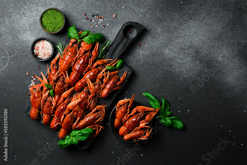 Hot spicy boiled crayfish and spices on a wooden board. On dark rustic background. Seafood and lobsters.
