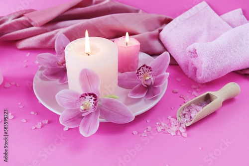 Fresh pink orchid flowers, burning candles, sea salt, on a bright pink background, spa concept, relaxation atmosphere, body care 