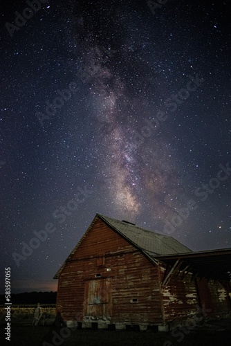 Mesmerizing vertical view of the magical starry night over an old wooden barn © Walker Winslow/Wirestock Creators