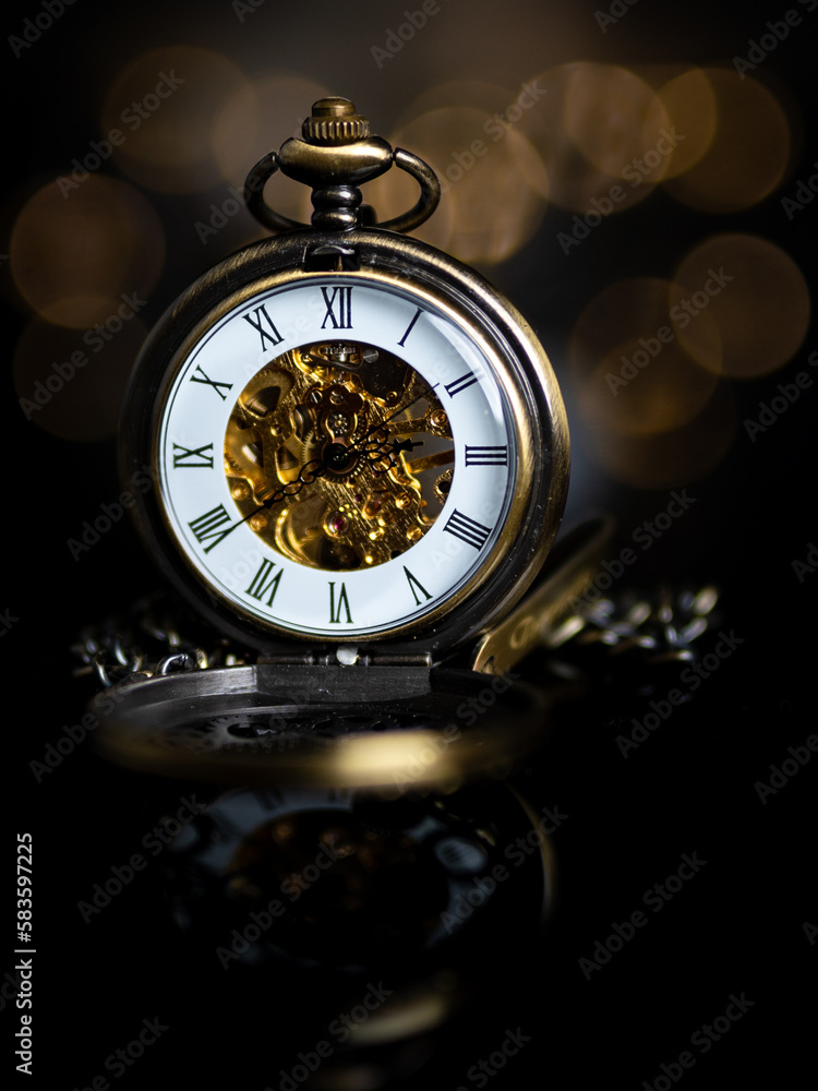 Vertical shot of an antique gold pocket watch isolated on a blurred background
