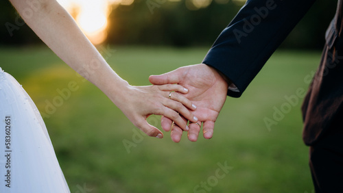 Close-up of bride and groom holding hands.