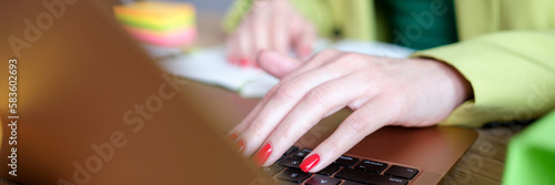 Female hands works on laptop keyboard in office