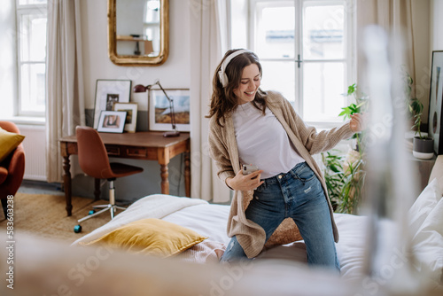 Young woman listening music trough headphones in her apartment.