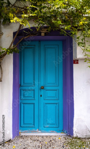 Old blue wooden door with violet frame in white wall. European architectural exterior poster.