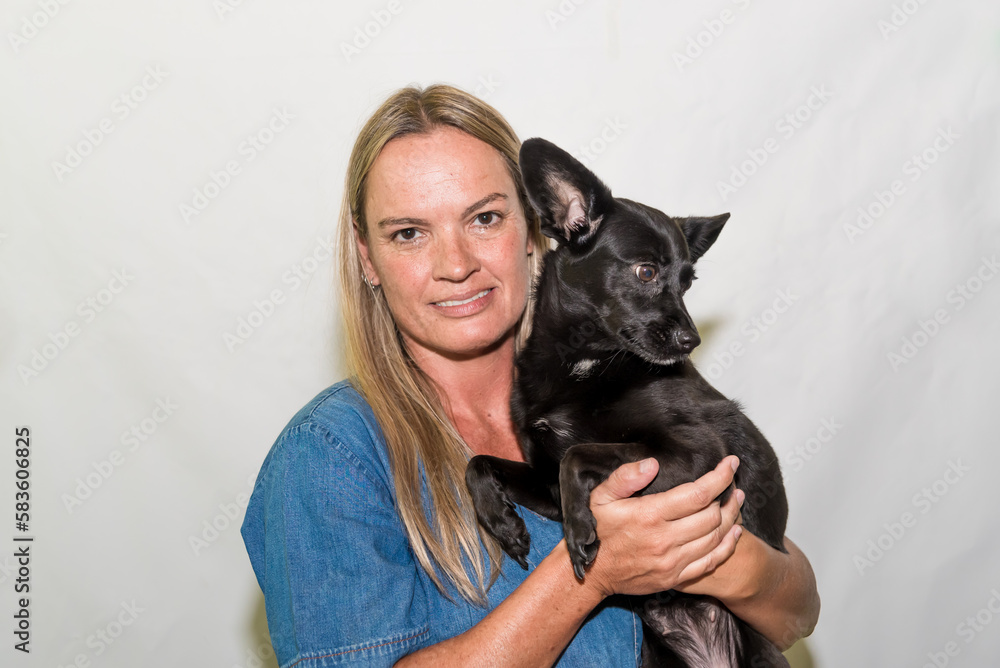 A woman holding a black dog in her arms adoption dog grooming A woman holding a black dog in her arms adoption dog grooming