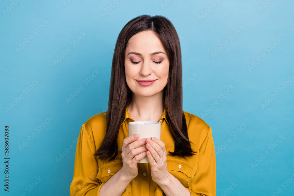 Photo of cute shiny woman wear yellow shirt smiling enjoying coffee aroma isolated blue color background Photo of cute shiny woman wear yellow shirt smiling enjoying coffee aroma isolated blue color background