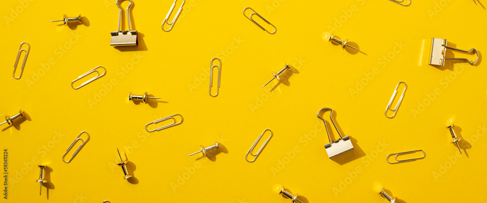 Stationery, paper clips, binders, buttons on a yellow background. Top view, flat lay. Banner Stationery, paper clips, binders, buttons on a yellow background. Top view, flat lay. Banner