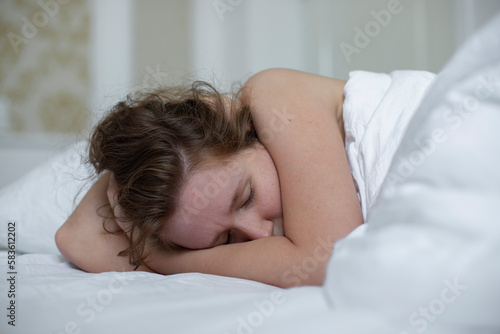Young sad depressed unhappy worried woman in the bed in bedroom at home in the morning lying under white blanket suffer from insomnia problems with sleep at night