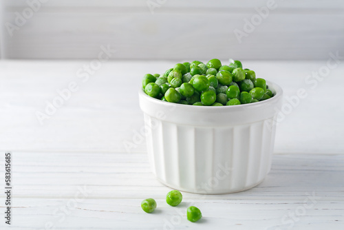 Freshly frozen green peas on a white wooden background