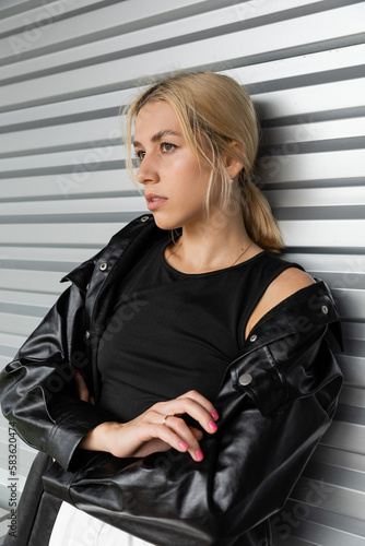 young blonde woman in leather shirt jacket standing near garage door in Miami.