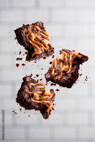 Flying chocolate caramel brownies on white background