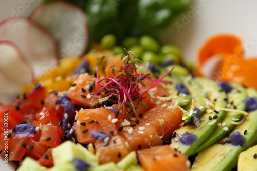Delicious poke bowl with salmon fish fillet and fresh vegetables. Exotic pescatarian food prepared for lunch in a cafe