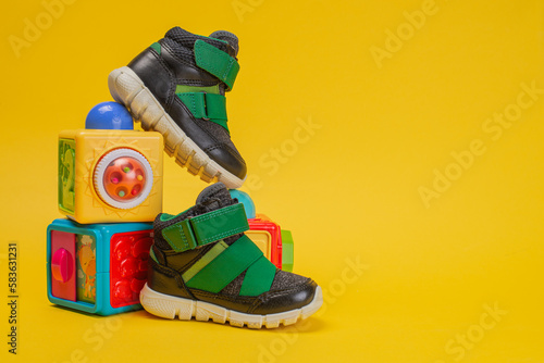 kids shoes with toys on yellow background.