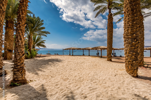Sandy beach resort and park area with palm trees near a shore of the Red Sea,...