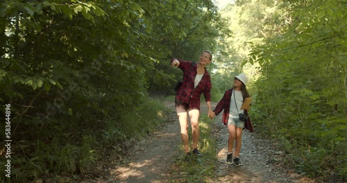 Mother and daughter hiking together in green forest