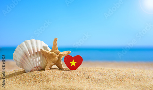 Beautiful beach of Vietnam. Flag of Vietnam in the shape of a heart and shells on a sandy beach.