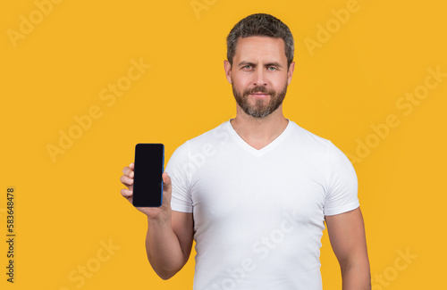 man showing phone screen isolated on yellow background. man showing phone screen