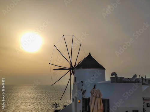 Traditional Greek windmill in Oia village on Santorini island, Greece in the late evening during a sunset