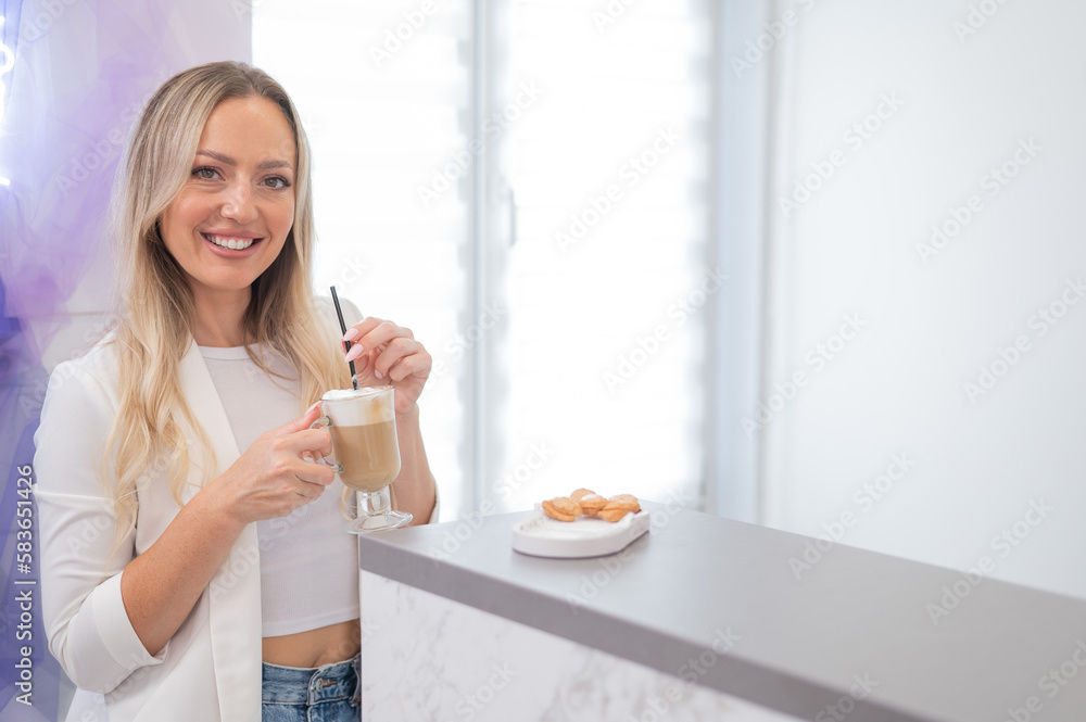Female client of a beauty salon drinking coffee at the reception desk. Female client of a beauty salon drinking coffee at the reception desk.