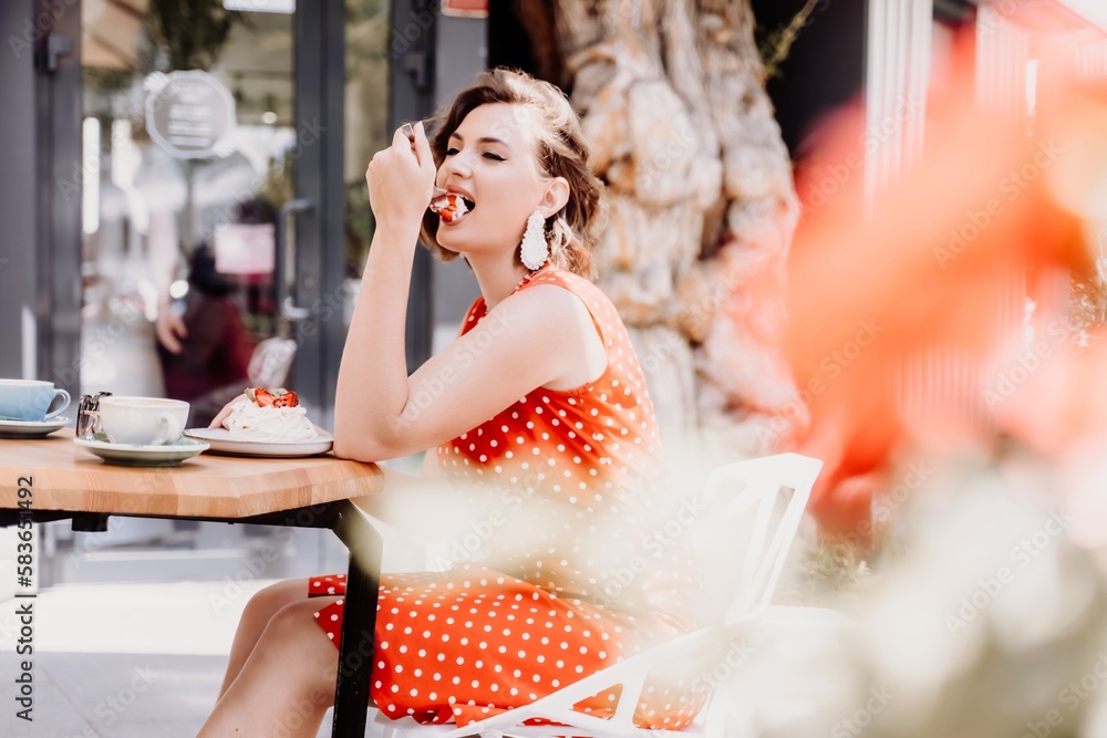 Charming woman in a restaurant, cafe on the street. She sits at the table and eats a cake with a fork. Dressed in a red sundress with white polka dots. Charming woman in a restaurant, cafe on the street. She sits at the table and eats a cake with a fork. Dressed in a red sundress with white polka dots.