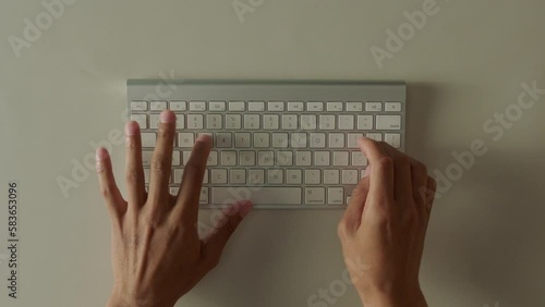 Caucasian hands typing on keyboard at white table