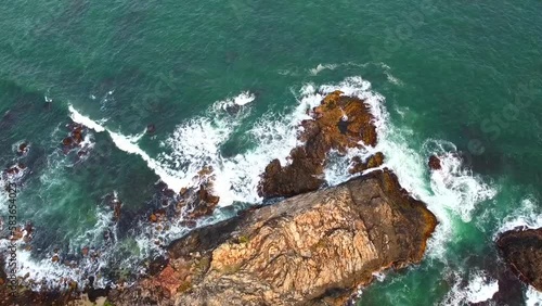 Aerial view from above of the sea waves at the rocky shore. Ocean coast. Calm beautiful video on the background for tourism, design and advertising