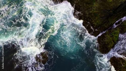 Aerial view from above of the sea waves at the rocky shore. Ocean coast. Calm beautiful video on the background for tourism, design and advertising