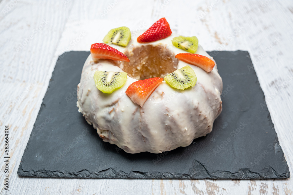 A gugelhupf (kuglof) with fruits on a black plate