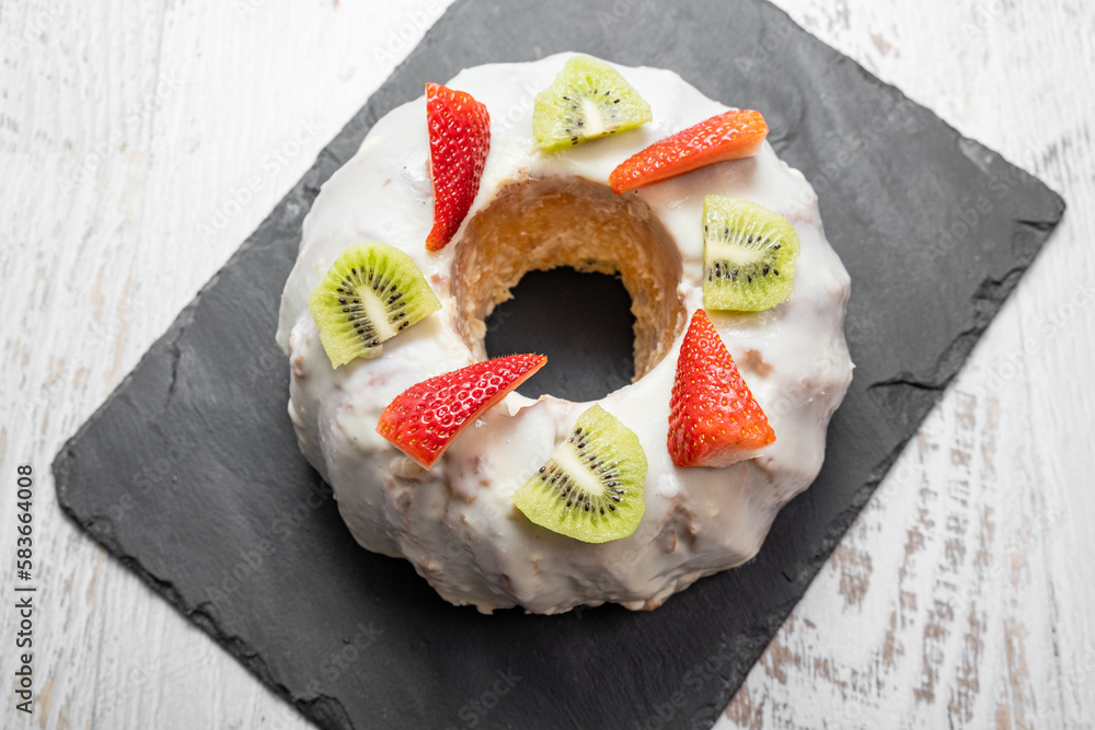 A gugelhupf (kuglof) with fruits on a black plate