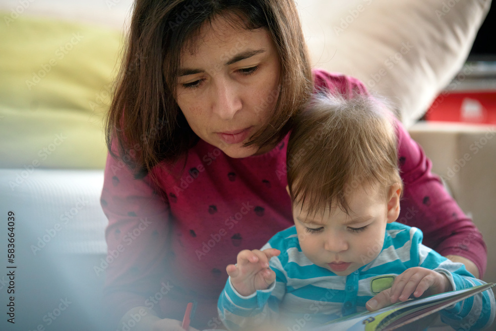 Mother And Baby Son Reading Book Together