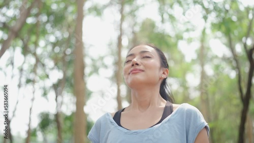 young Asian woman person breath a nature fresh air, relax and freedom lifestyle to happy in green park beautiful girl at summer travel and enjoy vacation with a tree outside for health careful