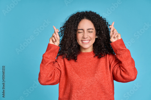 Fotografiet Young superstitious latin woman, girl student crossing fingers isolated on blue background