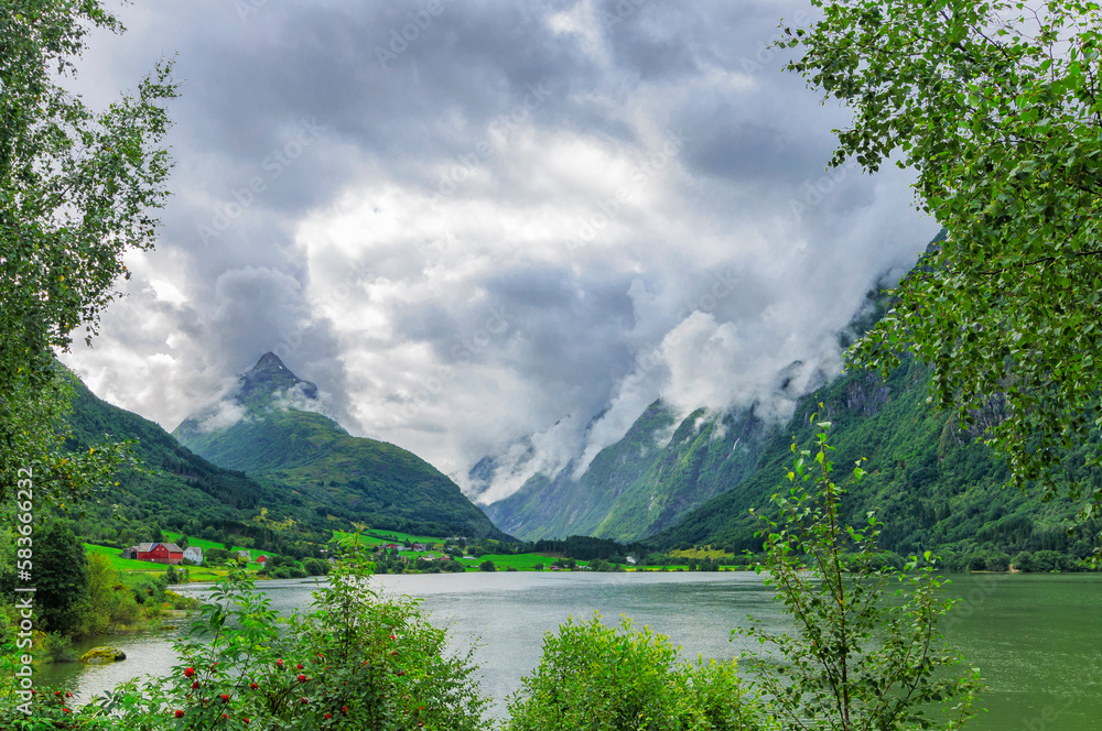 the hidden lake in the forest with mountains and clouds in Norway
