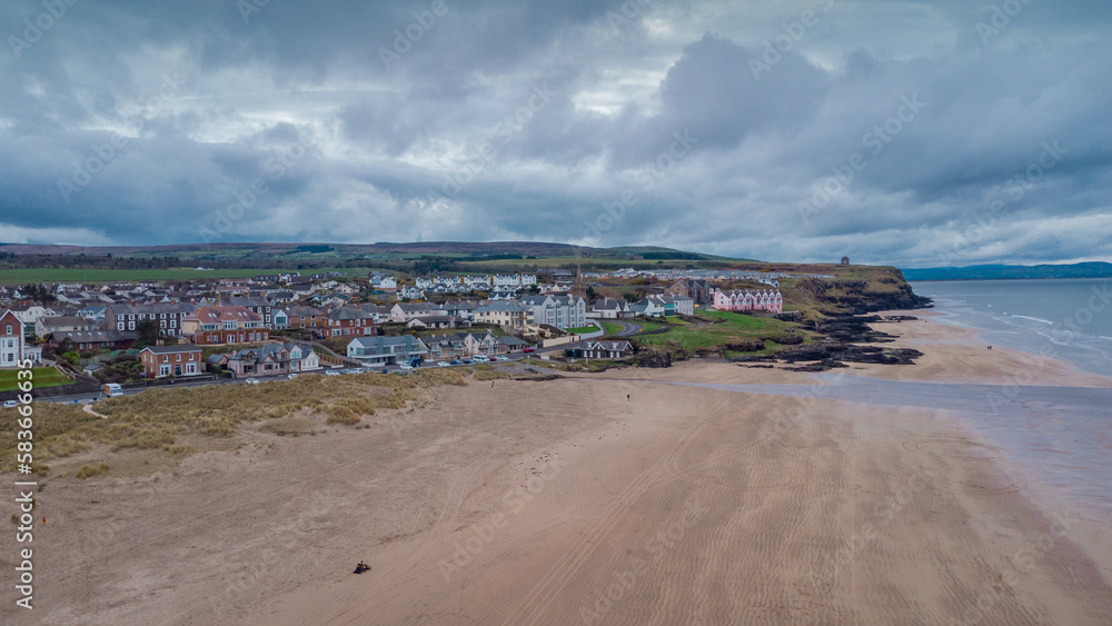 Aerial drone picturesque panorama of sandy beach at Castlerock, Northern Ireland on cloudy spring day. Dark clouds, wind and low tide at Castlerock coastal town.