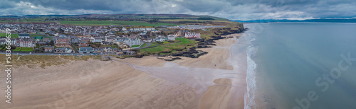 Aerial drone picturesque panorama of sandy beach at Castlerock, Northern Ireland on cloudy spring day. Dark clouds, wind and low tide at Castlerock coastal town.