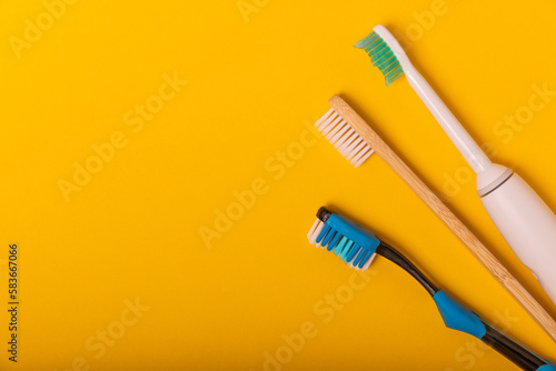 Electric and manual toothbrushes on a yellow background. View from above. Oral hygiene. Ordinary toothbrush  eco and electric toothbrush. Oral hygiene. Oral Care Kit. Dentist concept. Dental care.