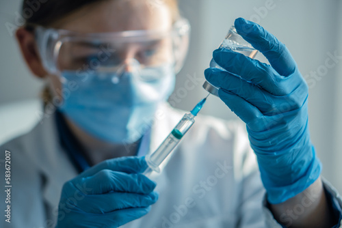 The doctor fills the syringe with medicine. A nurse in a hospital laboratory prepares for an injection. Concept: treatment, help, vaccine, vaccination, healthcare, pharmaceutics, medical laboratory.