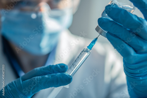 The doctor fills the syringe with medicine. A nurse in a hospital laboratory prepares for an injection. Concept: treatment, help, vaccine, vaccination, healthcare, pharmaceutics, medical laboratory.