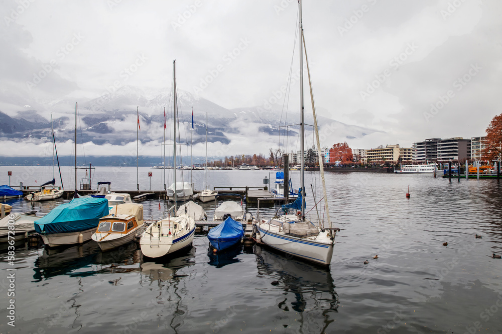 Fogging nature scene and sheltering sailboats and motorboats on lake Maggiore