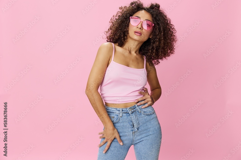 Happy woman afro curls hair dancing on pink background smile with teeth in summer pink t-shirt jeans and glasses, summer vibe, copy space - obrazy, fototapety, plakaty 