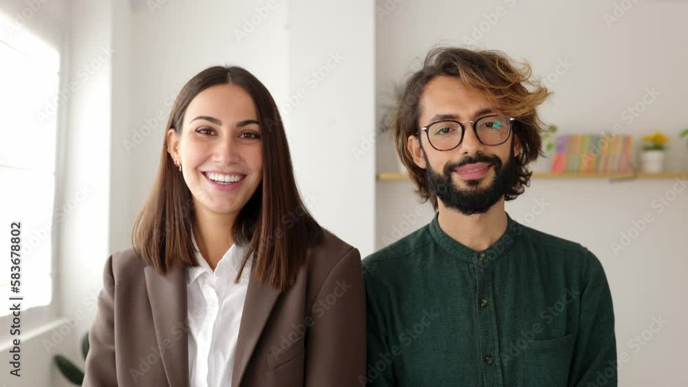 Smiling portrait of two young coworkers in the office. Businesswoman and businessman standing together at co-working workplace. Backwards camera movement. Smiling portrait of two young coworkers in the office. Businesswoman and businessman standing together at co-working workplace. Backwards camera movement.