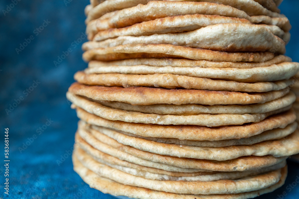 Flatbread lavash, chapati, naan, heap of tortilla on a blue background Homemade flatbread stacked. Flatbread lavash, chapati, naan, heap of tortilla on a blue background Homemade flatbread stacked.